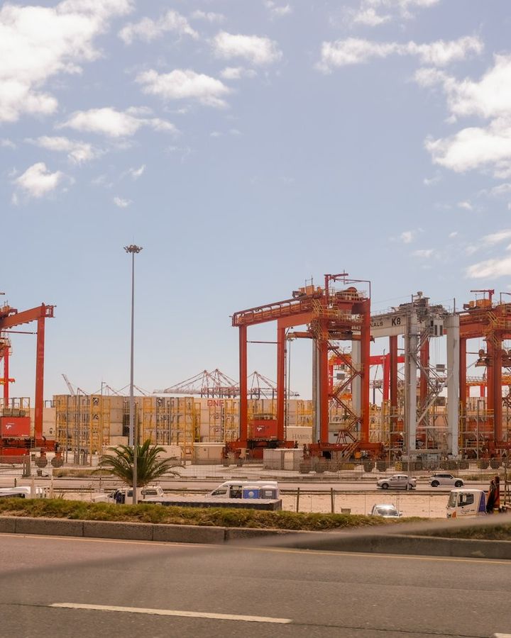 Red container cranes at a freight port under a blue sky